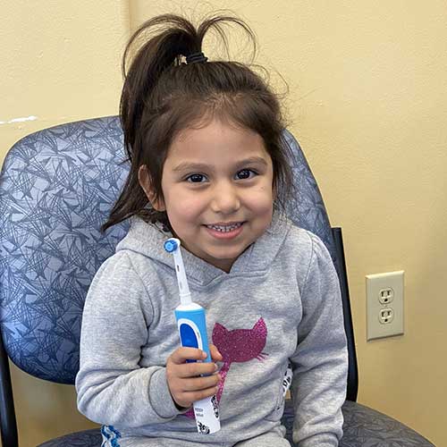 young girl smiling and holding toothbrush