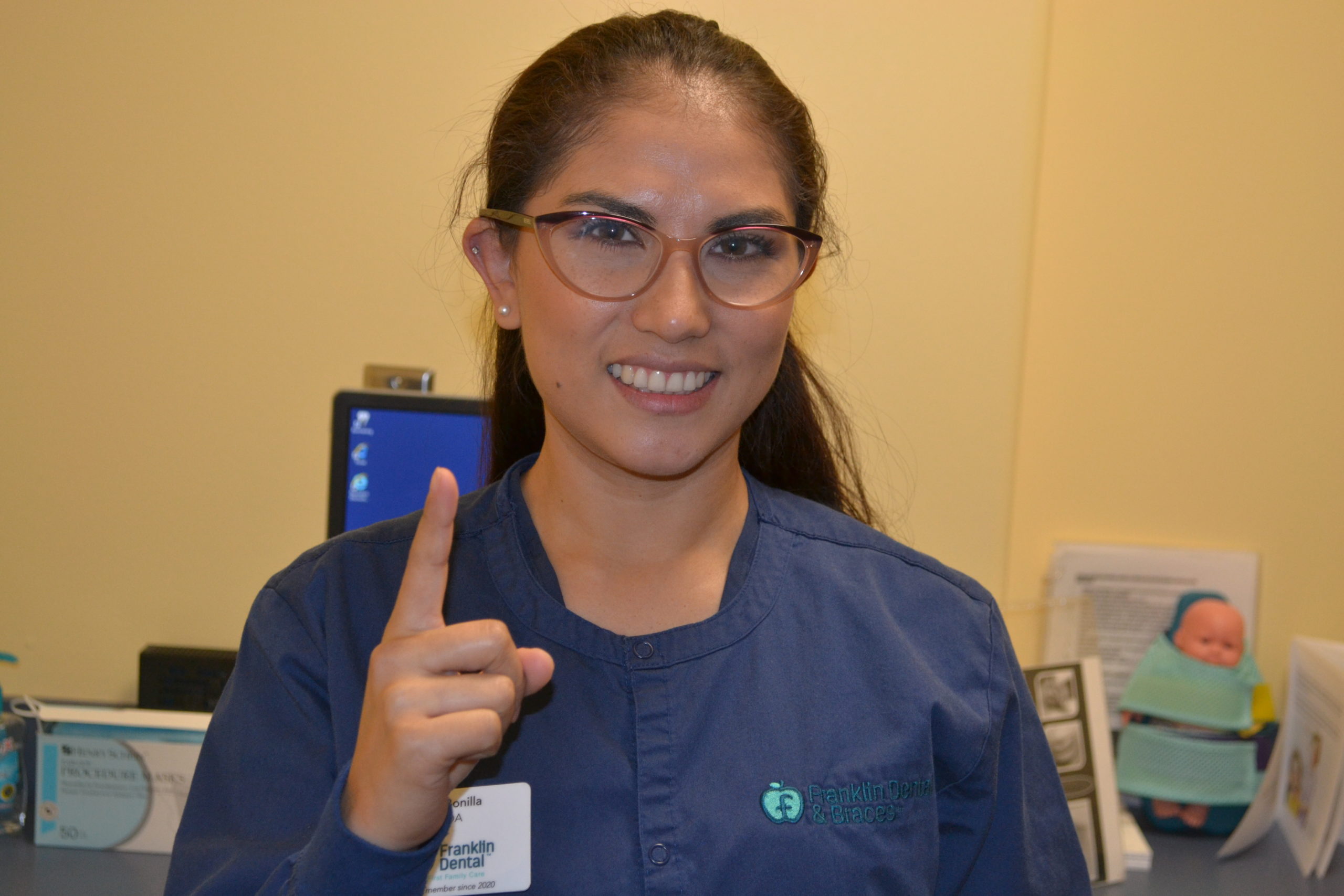 dentist smiling and holding up number one finger sign