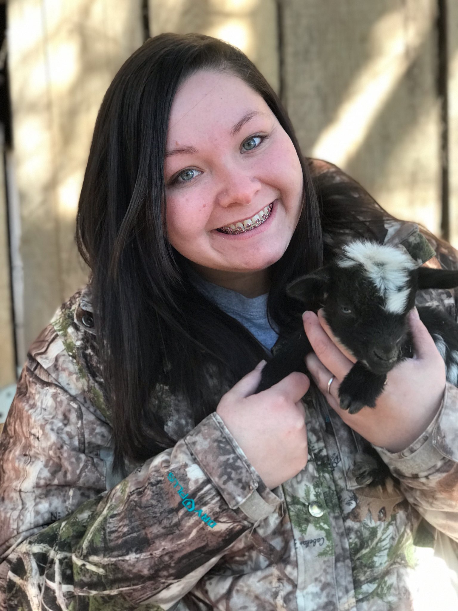 teen girl with braces holding goat