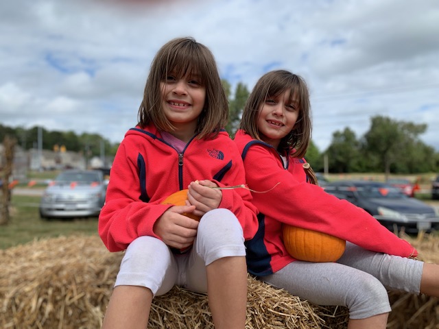 twin girls smiling on haystack